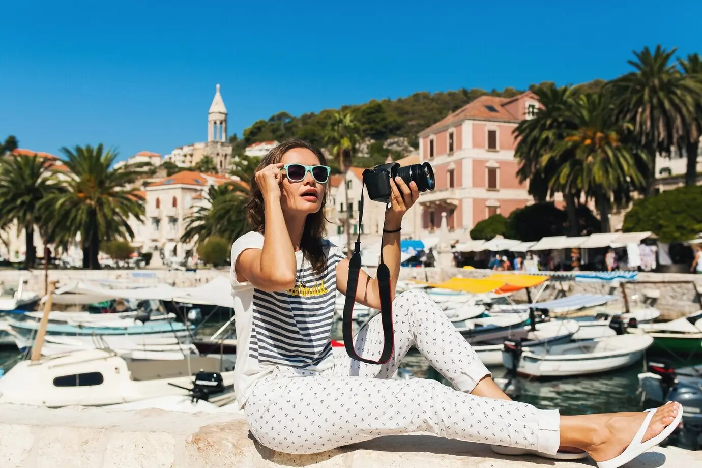 Mujer atractiva de vacaciones en Europa, junto al mar, en un crucero, tomando fotos con una cámara.