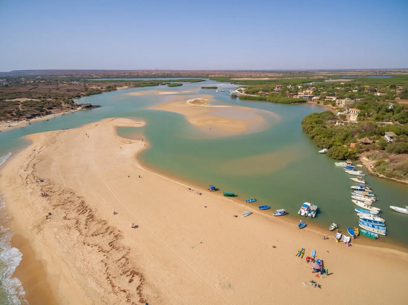 Vista desde lo alto de playas rodeadas de cruceros y vegetación, bajo un cielo azul en Senegal.
